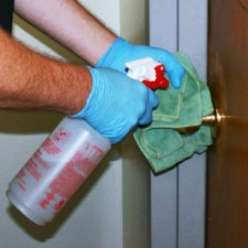 Image of a custodian's hands cleaning a doorknob.