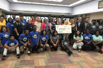 Photo of Upward Bound students, local and state representatives and officals from AT&amp;T standing together holding an oversized check for $10,000.