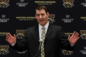 WMU head football coach Tim Lester gives a presentation in front of a Western Michigan University backdrop.