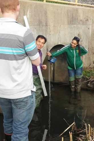 Students and professor measuring river