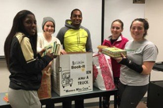 Photo of five WMU students from Phi Epsilon Kappa fraternity holding children's books donated for the campus United Way Book-It drive.